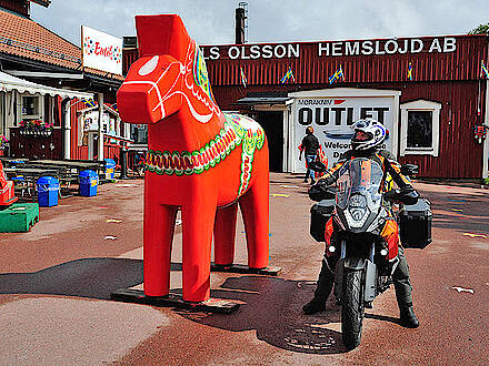Motorrad neben großem Holzpferd in Schweden