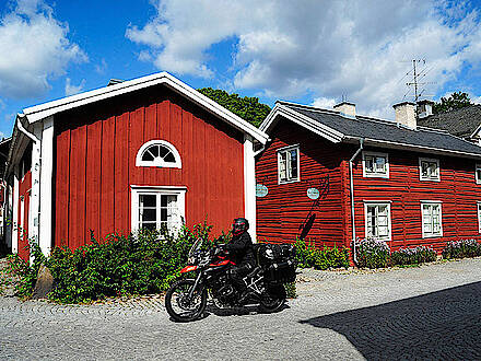 Motorrad vor rotem Holzhaus in Schweden