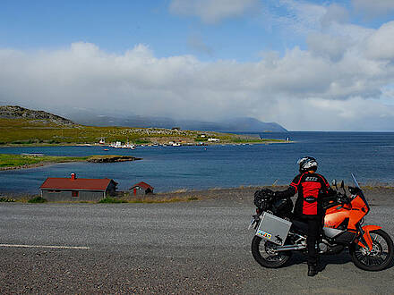 Motorradfahrer blickt über die Küste an der Barentssee in Norwegen