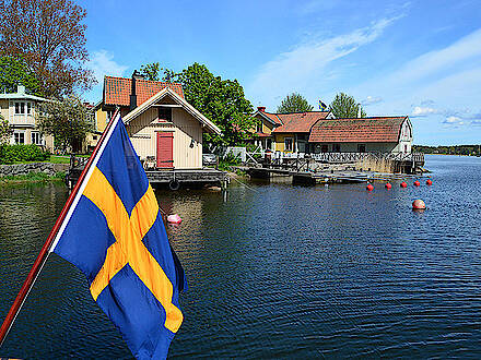 Kleine Holzhäuser mit schwedischer Fahne Flagge in den Schären von Stockholm