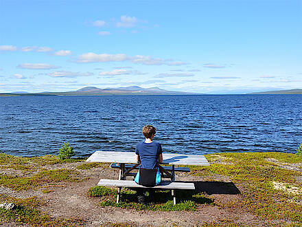 Eine Frau blickt sitzend auf den See Femunden