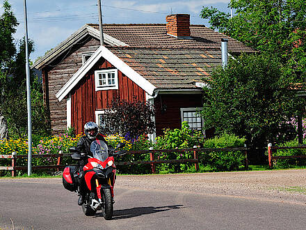 Motorrad vor rotem Holzhaus in Småland in Schweden