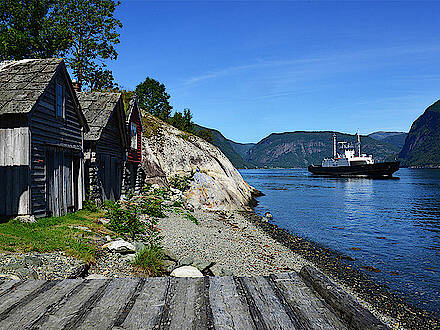 Fähre und Holzhäuser am Hardangerfjord in Norwegen