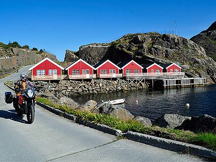 Motorrad vor roten Fischerhütten auf den Lofoten in Norwegen