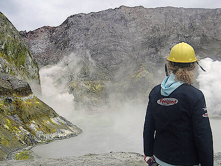 Motorradfahrerin vor dampfendem Vulkan in Neuseeland