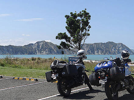 Motorräder auf einem Parkplatz vor einem See und Berg in Neuseeland