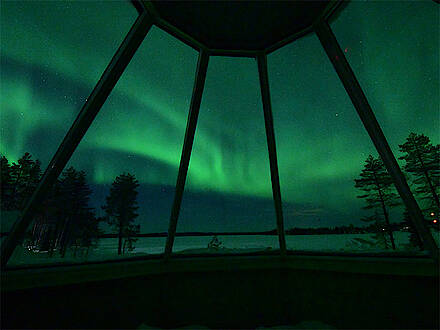 Polarlichter über dem Bett einer Skycabin in Finnland