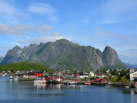 Blick auf ein Dorf auf den Lofoten vor einem Berg und Meer in Norwegen