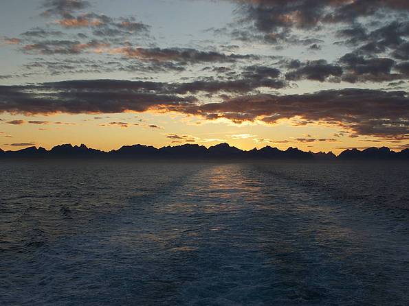 Die Lofoten zeichnen sich gegen den hellen Abendhimmel ab