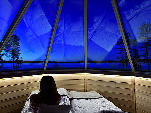 Eine Frau sitzt im Bett in einer Skycabin in Finnland