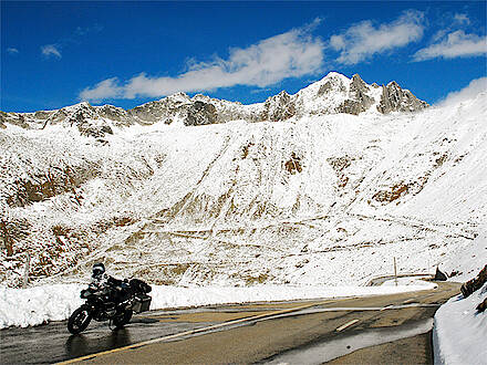 Motorrad steht vor Hochgebirgskulisse voller Schnee