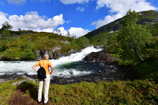 Eine Frau steht an einem Wasserfall auf dem Gaularfjell in Norwegen